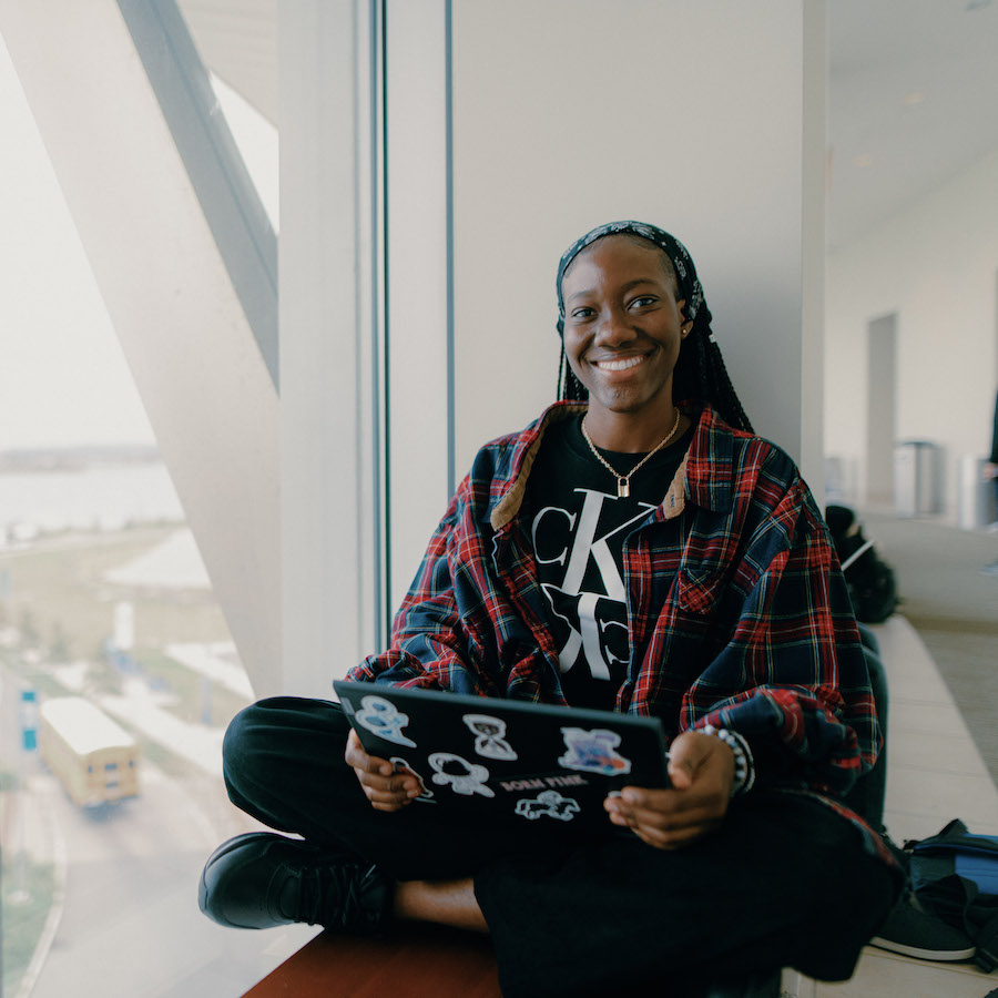 Student smiling and working on a laptop