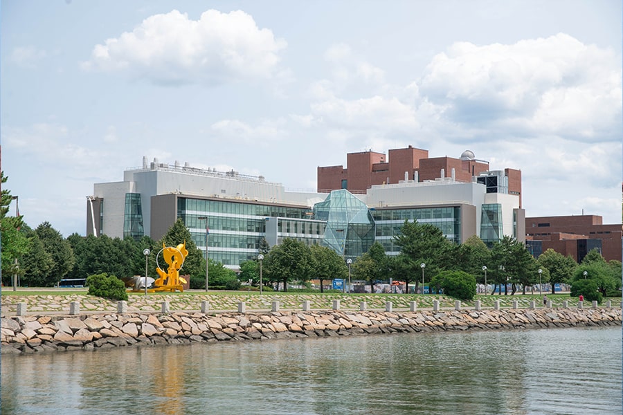 View of the Integrated Sciences Complex from Morrissey Blvd showing water in foreground.