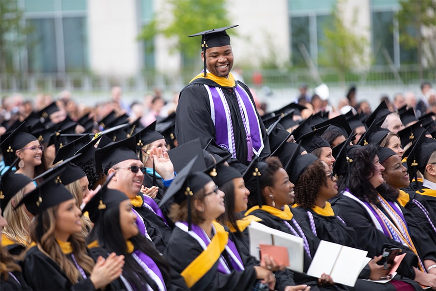 Graduate stands up in crowd at commencement