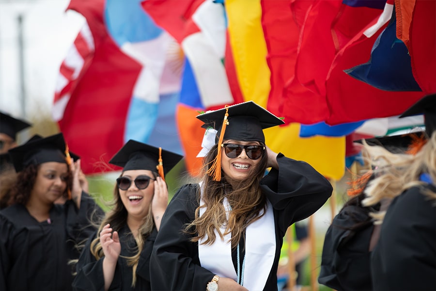 Students in graduation robes under international flags.