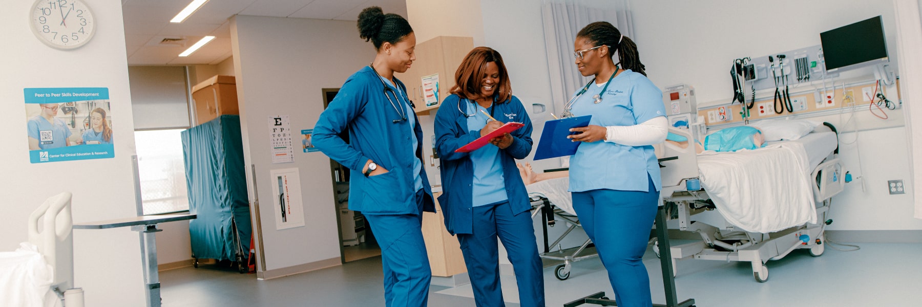 Three nursing in simulation lab  stand and compare notes.