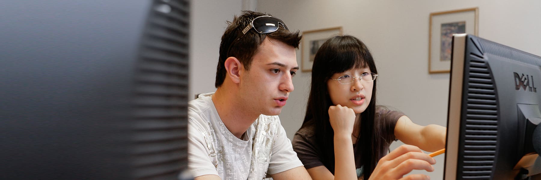 Two students work at a computer helping each other.