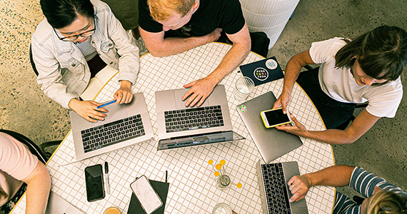 Group of students working together at desk, captured from above