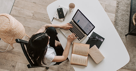 Student working at desk with laptop and open book