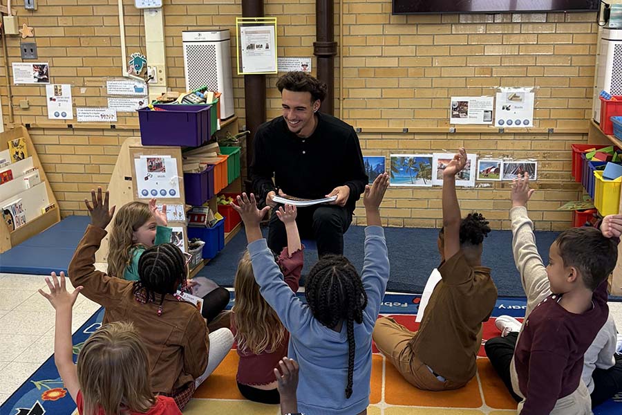 Student reading book to elementary school students