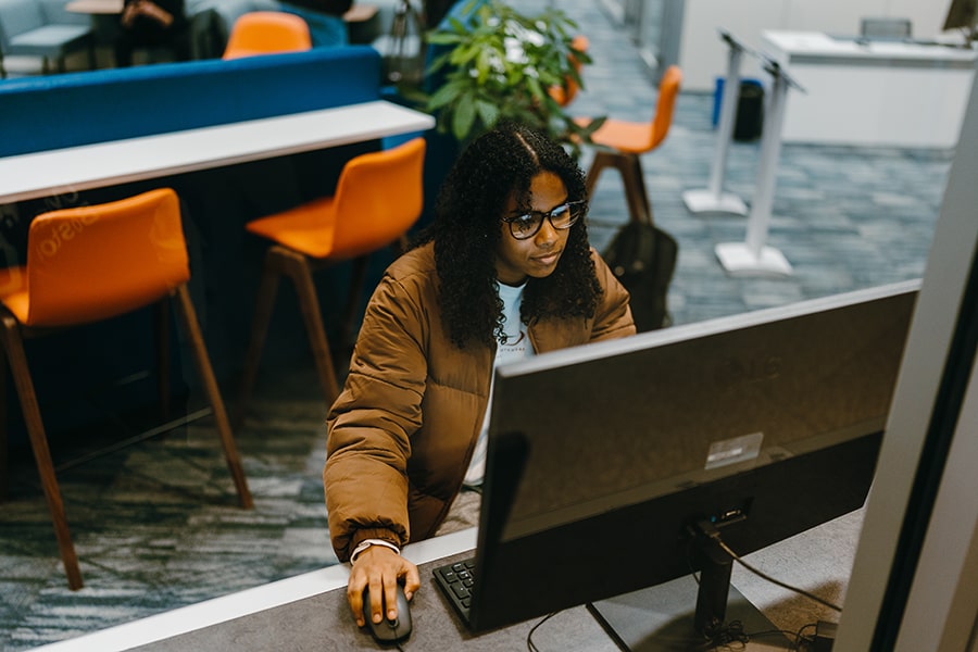 student in winter coat in front of computer at One Stop Office view from above