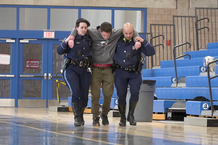 emergency preparedness simulation 2 officers aiding a person by holding him under arm on each side